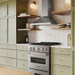ZLINE Convertible Vent Wall Mount Range Hood in Stainless Steel (KB) in a kitchen above a stainless steel range, light green cabinets, and wooden shelves.