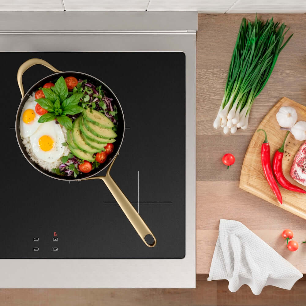 Frying pan with food on a ZLINE 30 in. 4.2 cu. ft. Paramount Induction Range with 4 Element Cooktop and Electric Convection Oven in Stainless Steel (SINR30), surrounded by vegetables on a wooden surface.