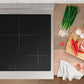 ZLINE Autograph Edition 30 in. 4.2 cu. ft. Paramount Induction Range with 4 Element Cooktop and Electric Convection Oven in Satin Stainless Steel with White Matte Door and Matte Black Accents (SINRSZ-WM-30-MB) next to a cutting board and vegetables on a wooden countertop