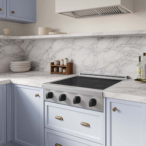 AZLINE Autograph Edition 30 in. Paramount Induction Rangetop with 4 Element Cooktop in Stainless Steel and Matte Black Accents (SINRTZ-30-MB), set into a light blue kitchen cabinet with a white marble backsplash and matching marble countertop.