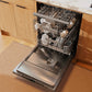 Open ZLINE 24 in. Monument Series 3rd Rack Dishwasher with Auto Door Open Drying, 44dBa, Satin Stainless Steel Panel (DWMT-SN-24) with clean dishes in a kitchen setting