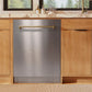 ZLINE Autograph Edition 24 in. Monument Series 3rd Rack Dishwasher with Auto Door Open Drying, 44dBa, Stainless Steel Panel with Champagne Bronze Handle (DWMTZ-304-24-CB) in a kitchen with wooden cabinets and a window view.