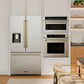 Modern kitchen with ZLINE Autograph Edition 36 in. 28.9 cu. ft. Standard-Depth French Door External Water Dispenser Refrigerator with Dual Ice Maker in Fingerprint-Resistant Stainless Steel and Champagne Bronze Traditional Handles (RSMZ-W-36-CB) and wall ovens.