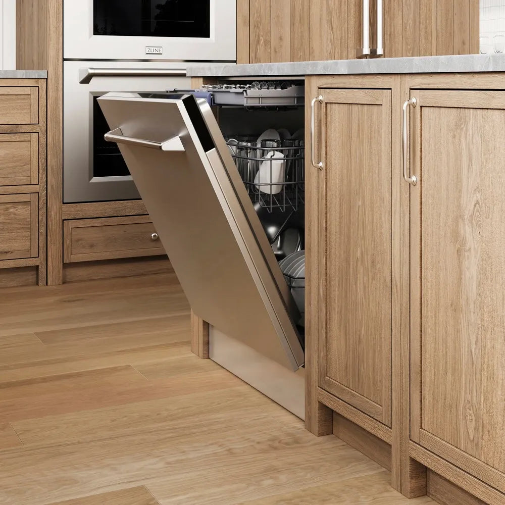 ZLINE 24 in. Tallac Series 3rd Rack Dishwasher with Auto Door Open Drying, 51dBa, Stainless Steel Panel (DWV-304-24) with its door open, showing the interior racks and dishes, installed in a modern kitchen with light oak wood cabinets and a wood-look floor.