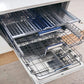 ZLINE Autograph Edition 24 in. Tallac Series 3rd Rack Dishwasher with Auto Door Open Drying, 51dBa, Panel Ready with Champagne Bronze Handle (DWVZ-24-CB) open in a kitchen setting with white cabinets and wooden floor.