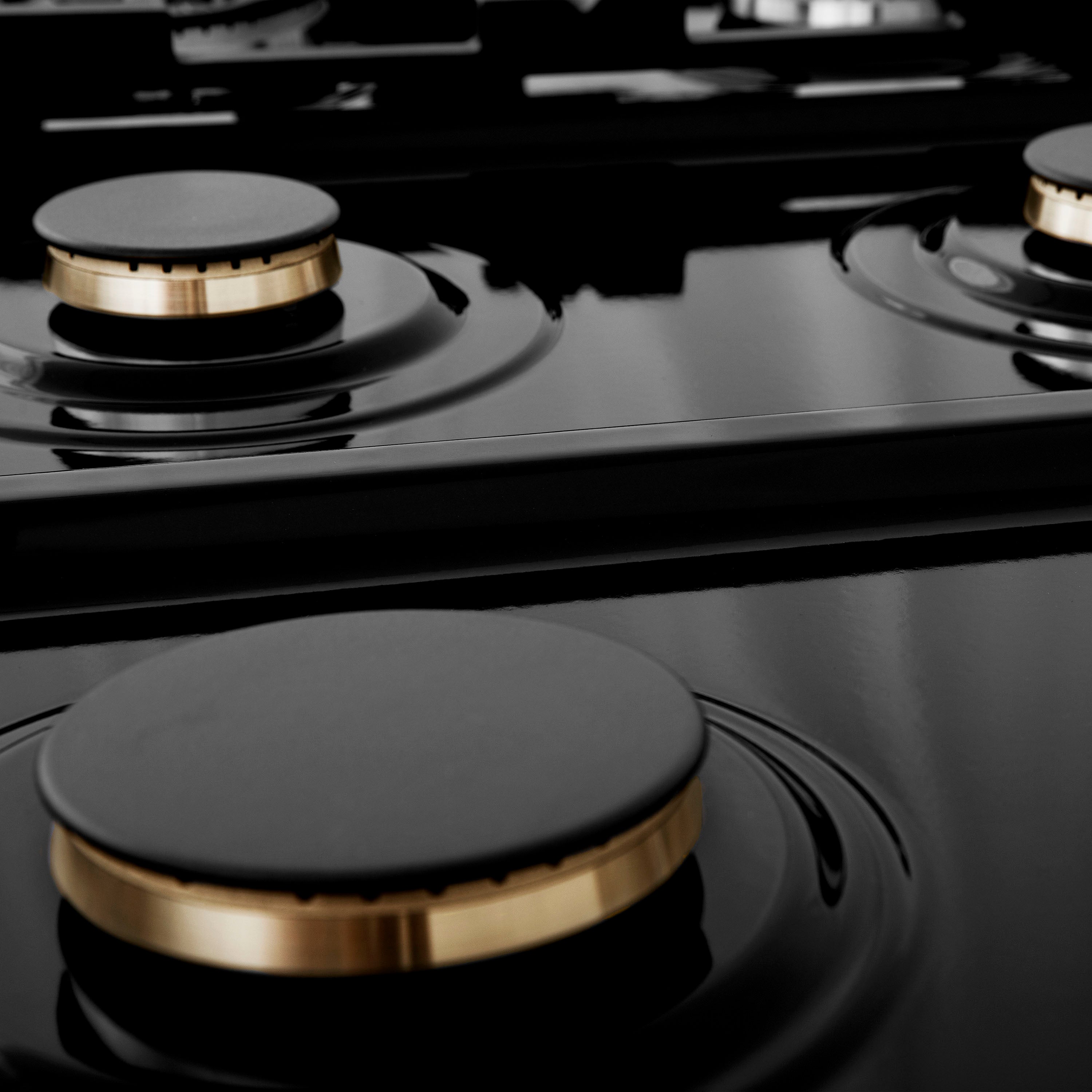 ZLINE brass burners on black porcelain cooktop with no grates.