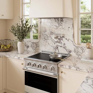 A modern kitchen scene featuring a ZLINE 30 in. 4.2 cu. ft. Marino Induction Range with 4 Element Cooktop and Electric Convection Oven in Stainless Steel with White Matte Door (MINR-WM-30) set into cream-colored cabinetry with a white and gray marble backsplash and countertop.