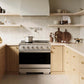 A ZLINE 36 in. 5.2 cu. ft. Marino Induction Range with 5 Element Cooktop and Electric Convection Oven in Stainless Steel (MINR36) installed in a modern kitchen with light wood cabinets, beige countertops, and a tiled backsplash.