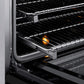 ZLINE 36 in. 5.2 cu. ft. Paramount Induction Range with 5 Element Cooktop and Electric Convection Oven in Satin Stainless Steel with Black Matte Door (SINRS-BLM-36) close-up, open oven with racks extended, showing interior components.