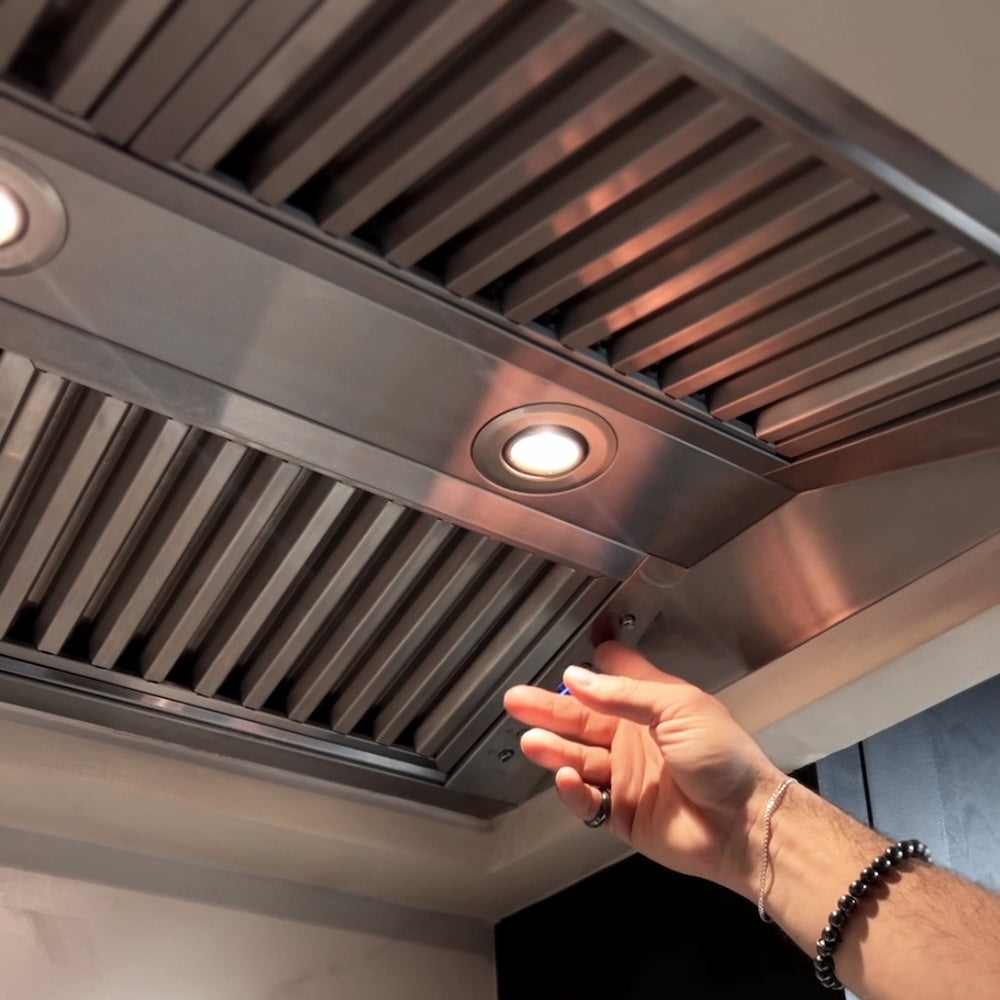 ZLINE Ducted Wall Mount Range Hood Insert in Outdoor Approved Stainless Steel (721-304) hand reaching towards lights and buttons.
