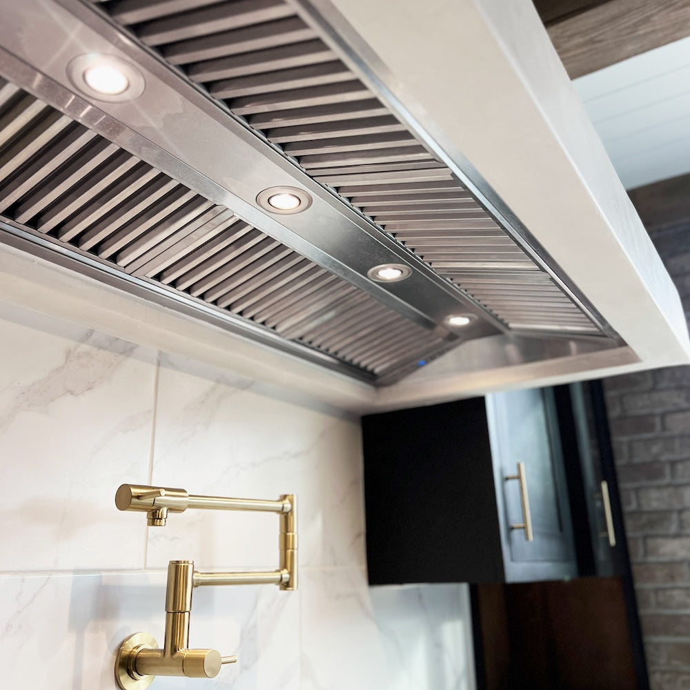 ZLINE Ducted Wall Mount Range Hood Insert in Outdoor Approved Stainless Steel (721-304) in a modern kitchen setting with gold pot filler faucet. 46-inch model shown.