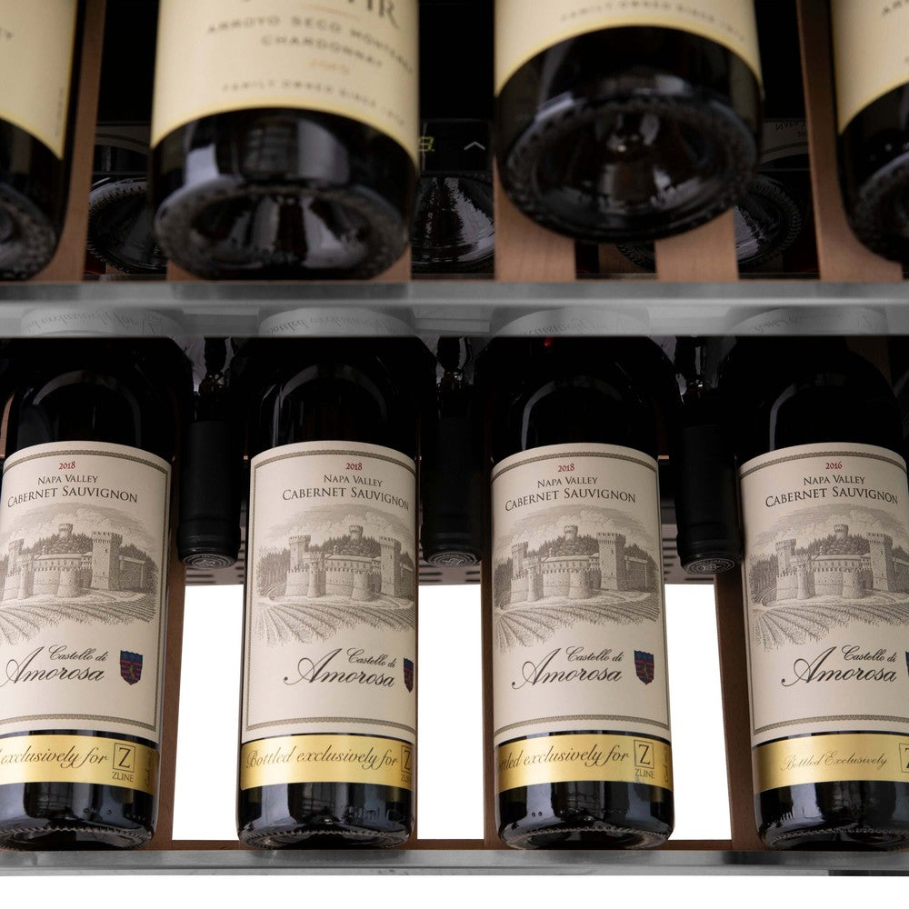 ZLINE Autograph Edition 24 in. Monument Dual Zone 44-Bottle Wine Cooler in Stainless Steel with Polished Gold Accents (RWVZ-UD-24-G) close-up, four bottles of Cabernet Sauvignon on extended wood shelf from above.
