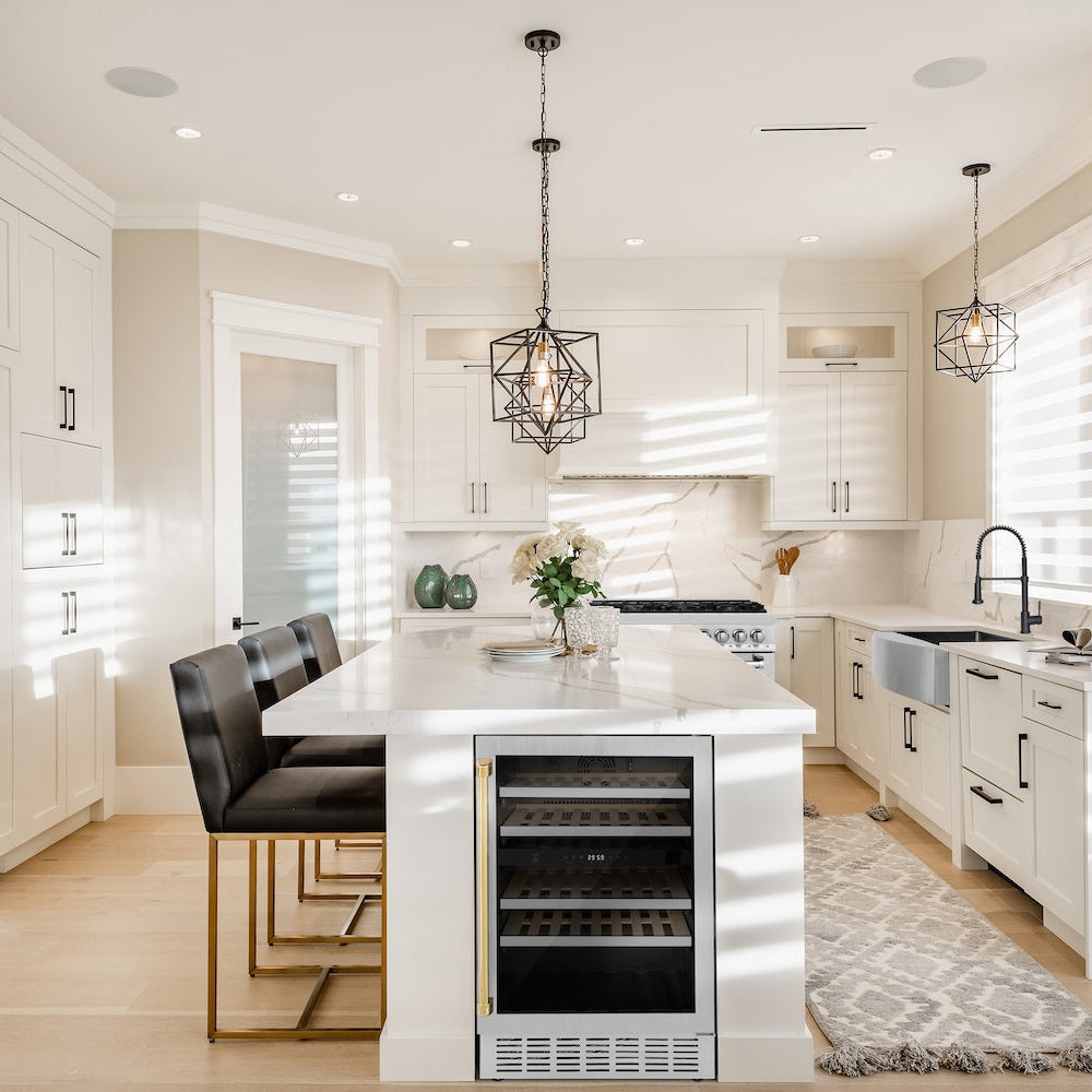 ZLINE Autograph Edition 24 in. Monument Dual Zone 44-Bottle Wine Cooler in Stainless Steel with Polished Gold Accents (RWVZ-UD-24-G) in a kitchen with white cabinets, marble countertops, and an island.