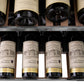 ZLINE Autograph Edition 24 in. Monument Dual Zone 44-Bottle Wine Cooler in Stainless Steel with Matte Black Accents (RWVZ-UD-24-MB) close-up, four bottles of Cabernet Sauvignon on extended wood shelf from above.