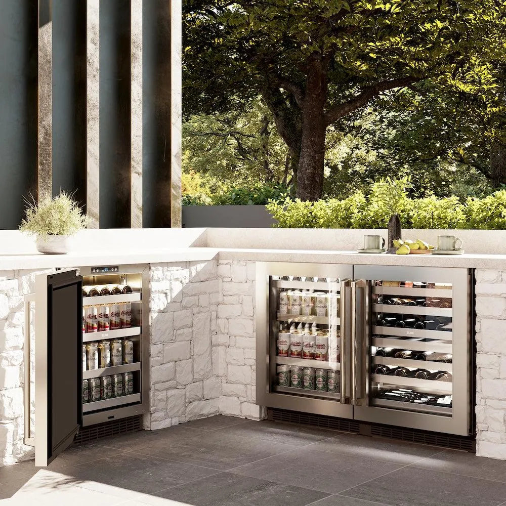 ZLINE 24 in. Touchstone 151 Can Beverage Fridge With Stainless Steel Glass Door (RBSO-GS-24) side, in an outdoor patio area against a stone wall and greenery.