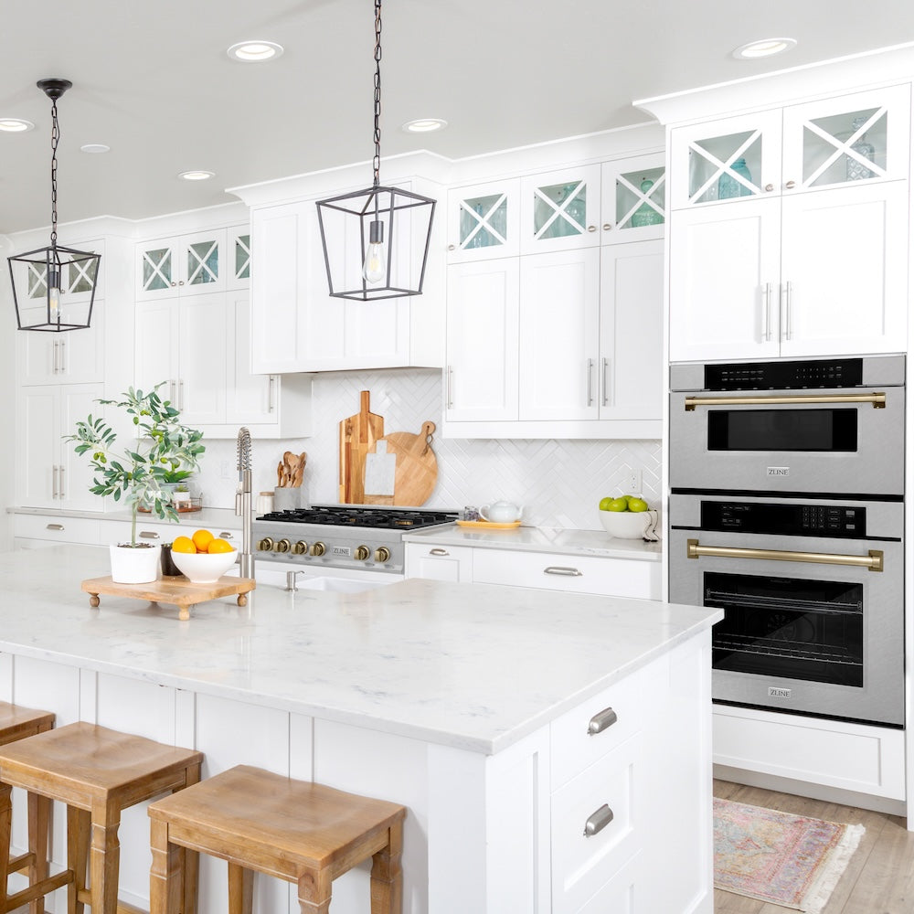 ZLINE Autograph Edition 30 in. 1.2 cu. ft. Built-In Microwave Drawer in Satin Stainless Steel with Champagne Bronze Accents (MWDZ-30-SS-CB) in a modern kitchen with white cabinets, matching stainless steel appliances, and wooden stools.