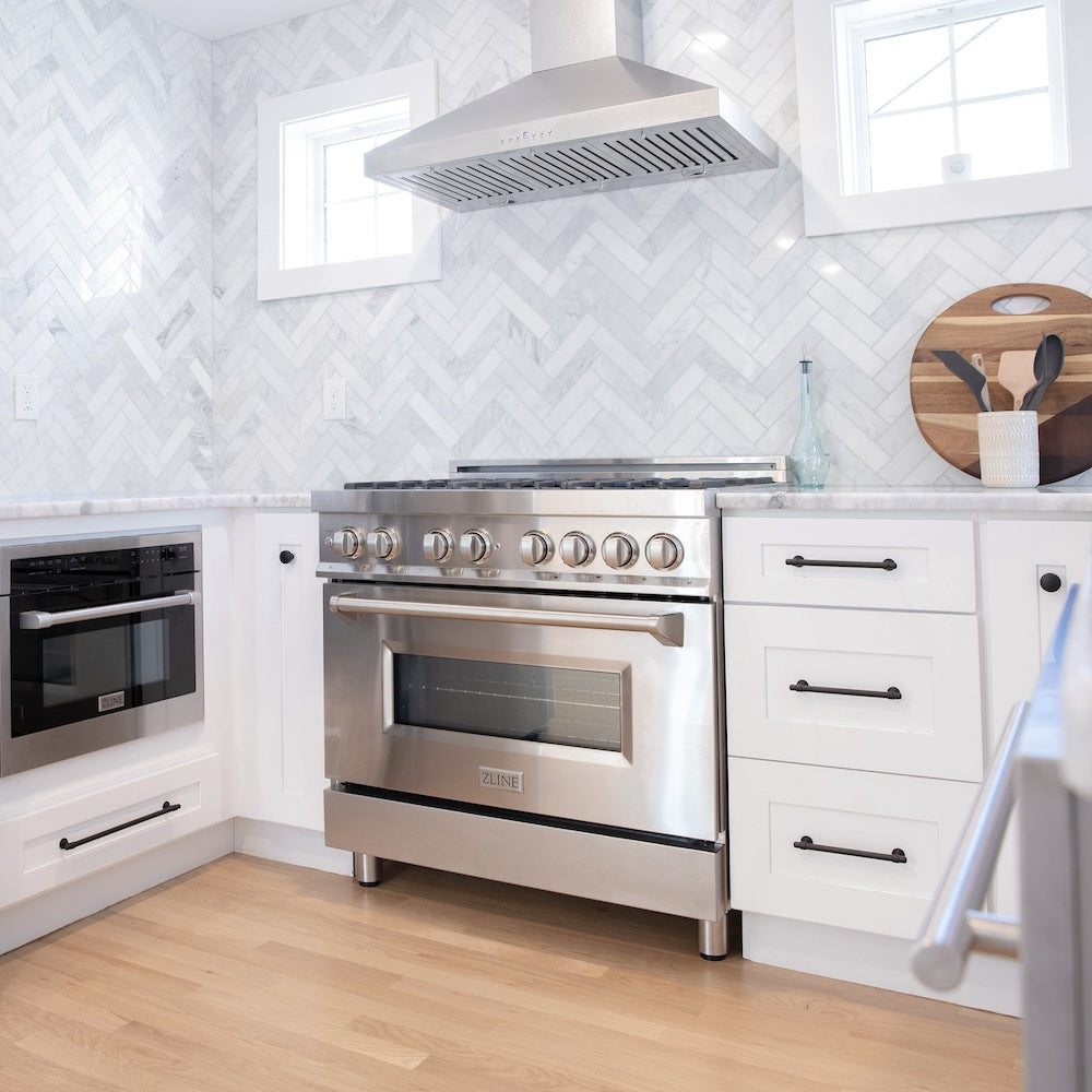 ZLINE Convertible Vent Wall Mount Range Hood in Satin Stainless Steel with Size Options (8KL3S) in a kitchen with stainless steel range and white cabinets