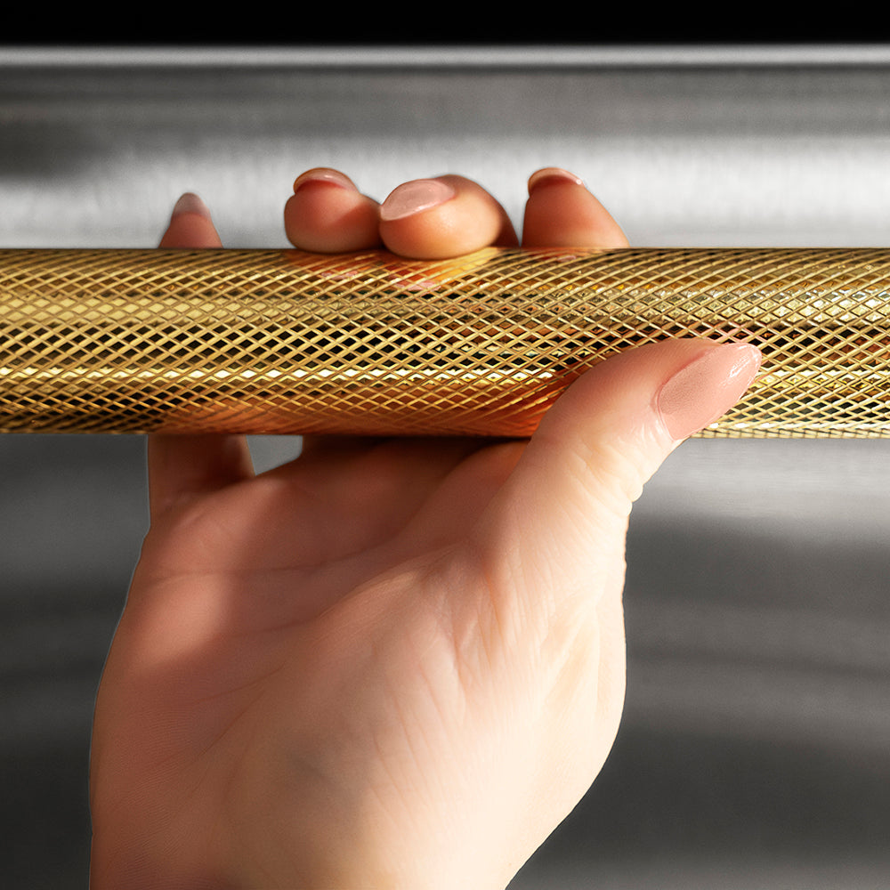 ZLINE Autograph Edition 24 in. Monument Series 3rd Rack Dishwasher with Auto Door Open Drying, 44dBa, Stainless Steel Panel with Polished Gold Helix Handle (DWMTZ-30424-KG), close-up, person holding Helix handle showing knurled diamond texture.