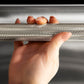 ZLINE Autograph Edition 24 in. Monument Series 3rd Rack Dishwasher with Auto Door Open Drying, 44dBa, Stainless Steel Panel with Polished Nickel Helix Handle (DWMTZ-30424-KPN), close-up, person holding Helix handle showing knurled diamond texture.