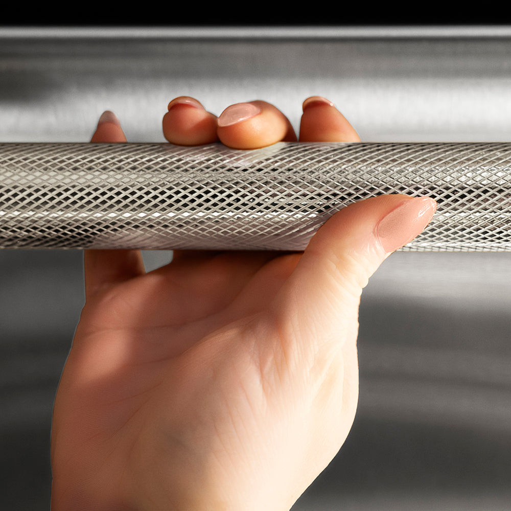 ZLINE Autograph Edition 24 in. Monument Series 3rd Rack Dishwasher with Auto Door Open Drying, 44dBa, Stainless Steel Panel with Polished Nickel Helix Handle (DWMTZ-30424-KPN), close-up, person holding Helix handle showing knurled diamond texture.