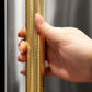 ZLINE Autograph Edition 60 in. 32.2 cu. ft. French Door Built-In Bottom Freezer Refrigerator with Water Dispenser and Ice Maker in Stainless Steel with Graphite Gray Interior and Polished Gold Helix Handles (GRBIVZ-30460KG) hand holding Helix handle showing knurled diamond texture.