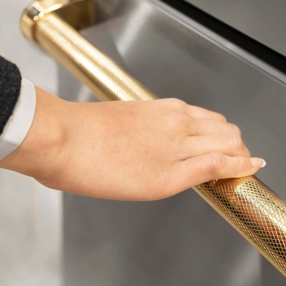 ZLINE Autograph Edition 36 in. 19.6 cu. ft. French Door Built-In Bottom Freezer Refrigerator with Water Dispenser and Ice Maker in Stainless Steel with Graphite Gray Interior and Polished Gold Helix Handles (GRBIVZ-30436KG) hand holding Helix handle showing knurled diamond texture.