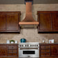 ZLINE Designer Series Hand-Hammered Copper Wall Mount Range Hood in a rustic kitchen with brown cabinets front.