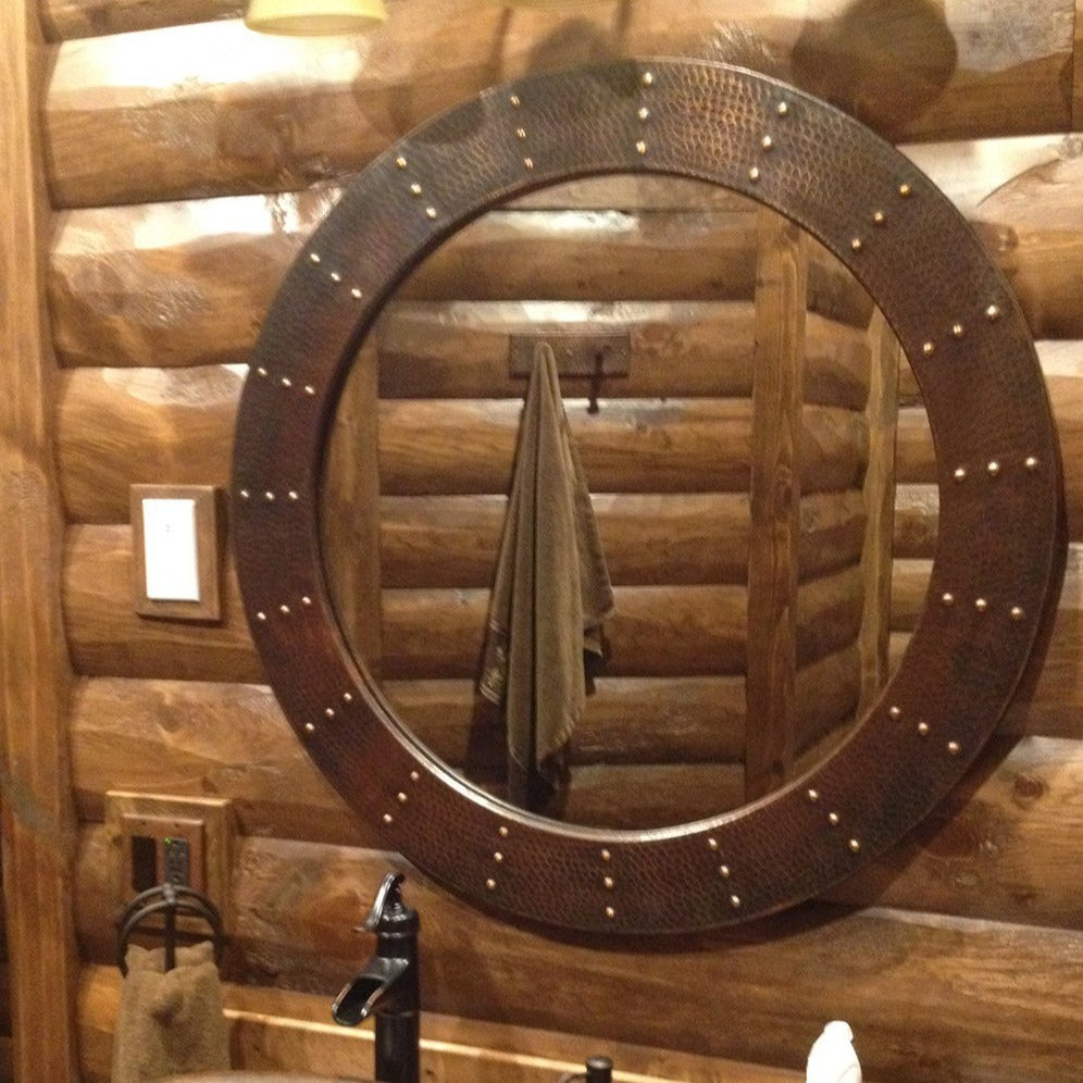 34" Round Hammered Copper Mirror - with Rivet Embellishments in a wooden-themed bathroom