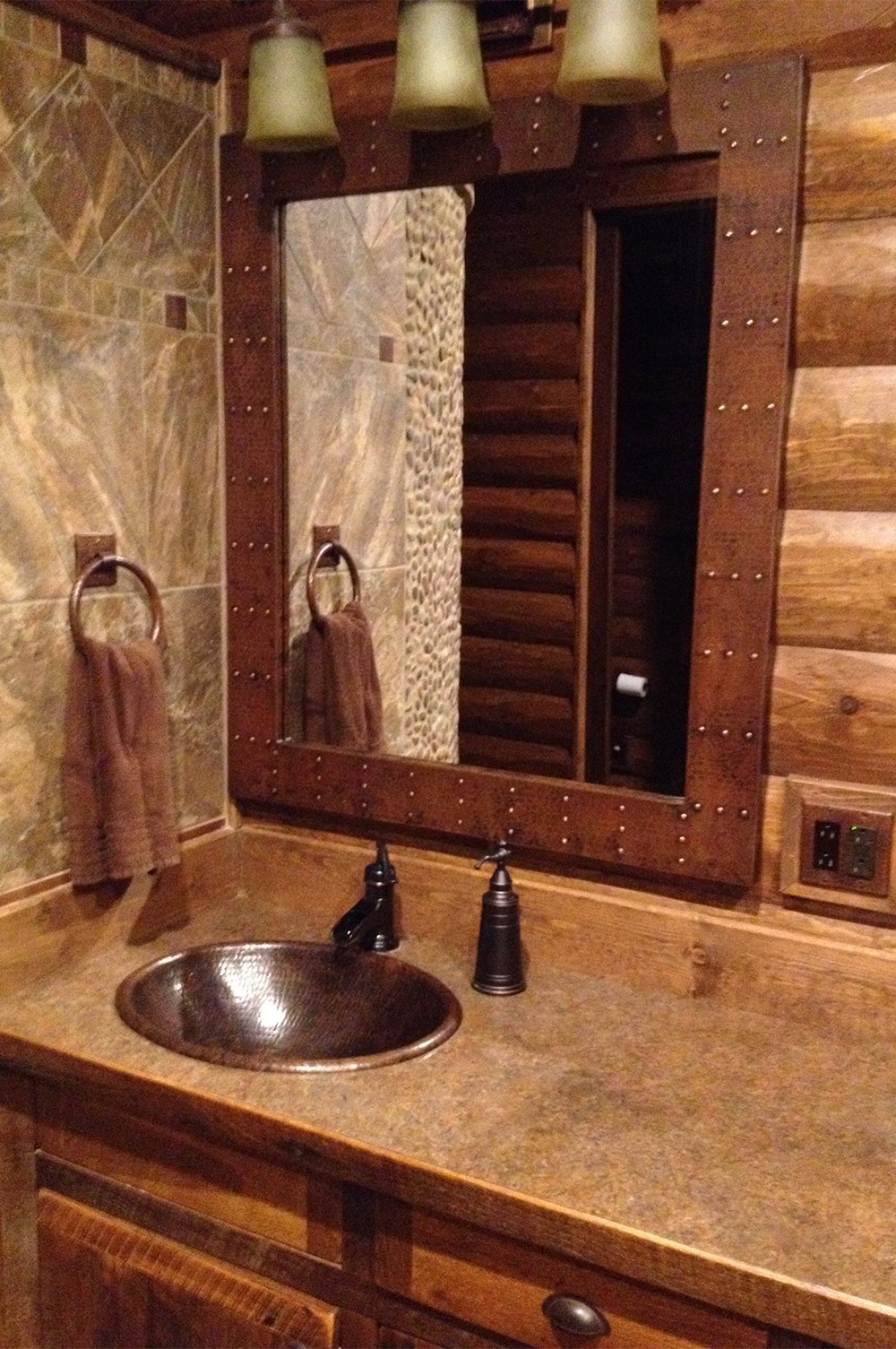36" Rectangle Hammered Copper Mirror with rivet embellishments in a log cabin bathroom