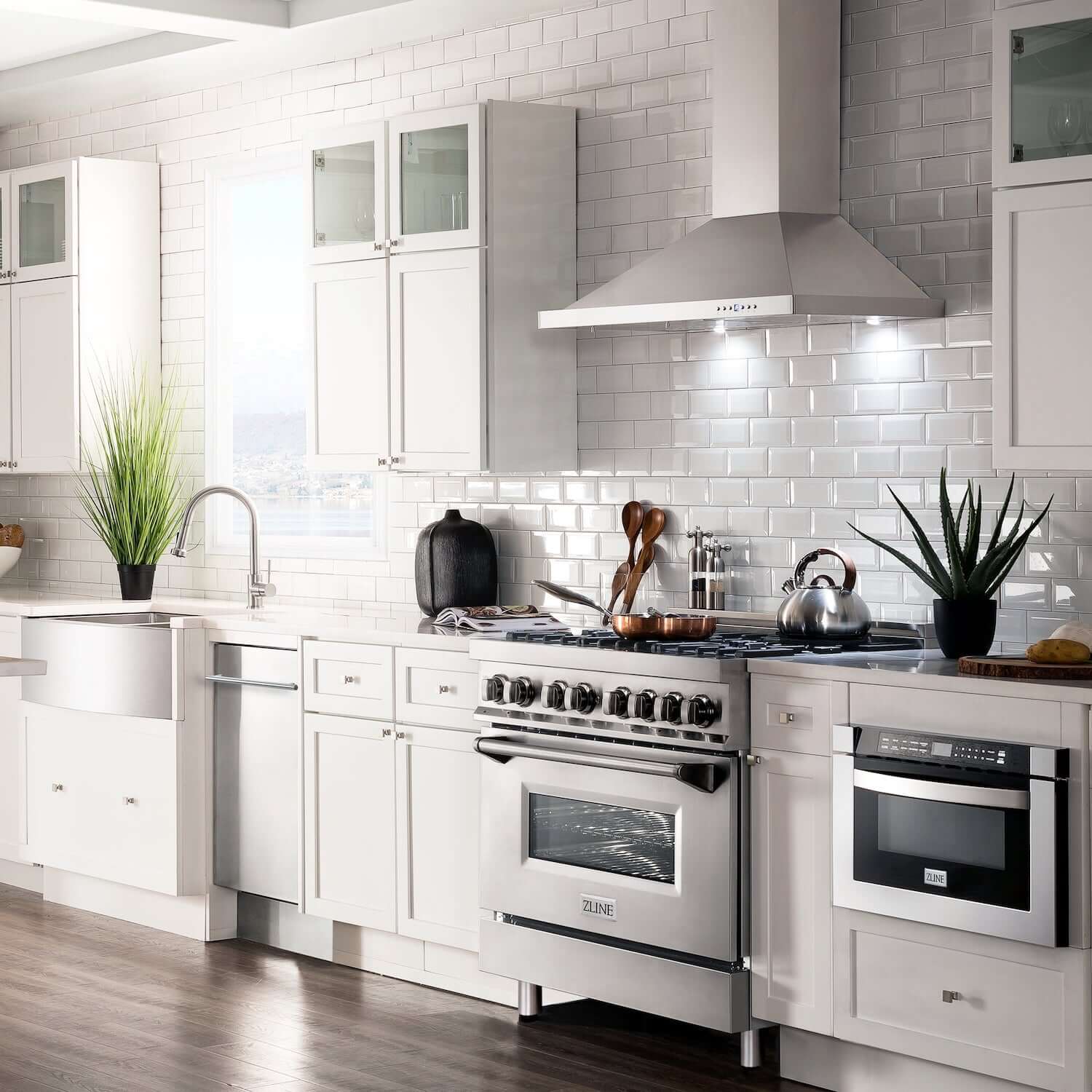 ZLINE range hood, range, microwave drawer, dishwasher, sink, and faucet in white cottage-style kitchen.