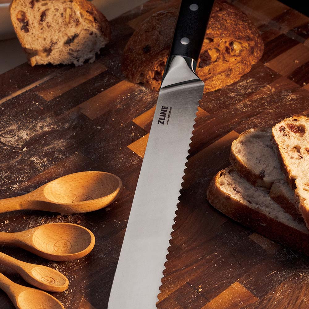 ZLINE bread knife on cutting board with wooden spoons and sourdough loaf