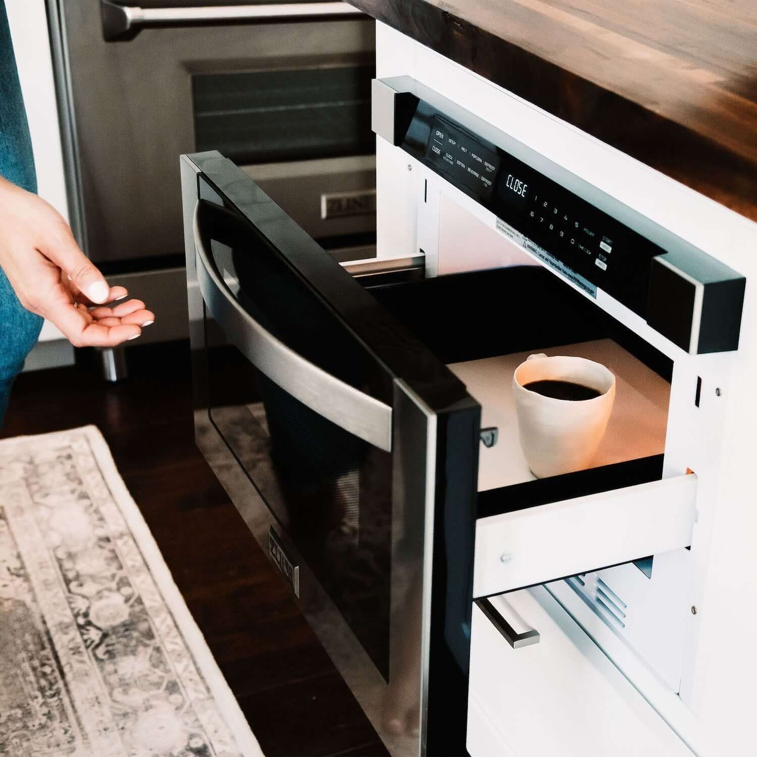 Built- in microwave drawer with a cup of coffee inside being opened.