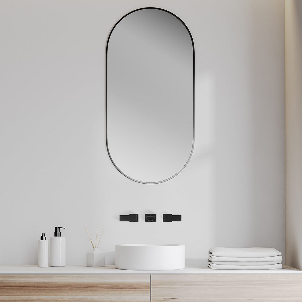 Matte Black Bliss wall mount bath faucet in a luxury bathroom with large oval mirror