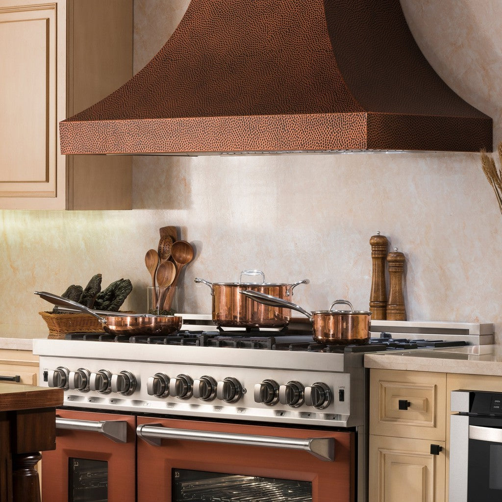 ZLINE Designer Series Hand-Hammered Copper Wall Mount Range Hood in a rustic kitchen with wood cabinets side.