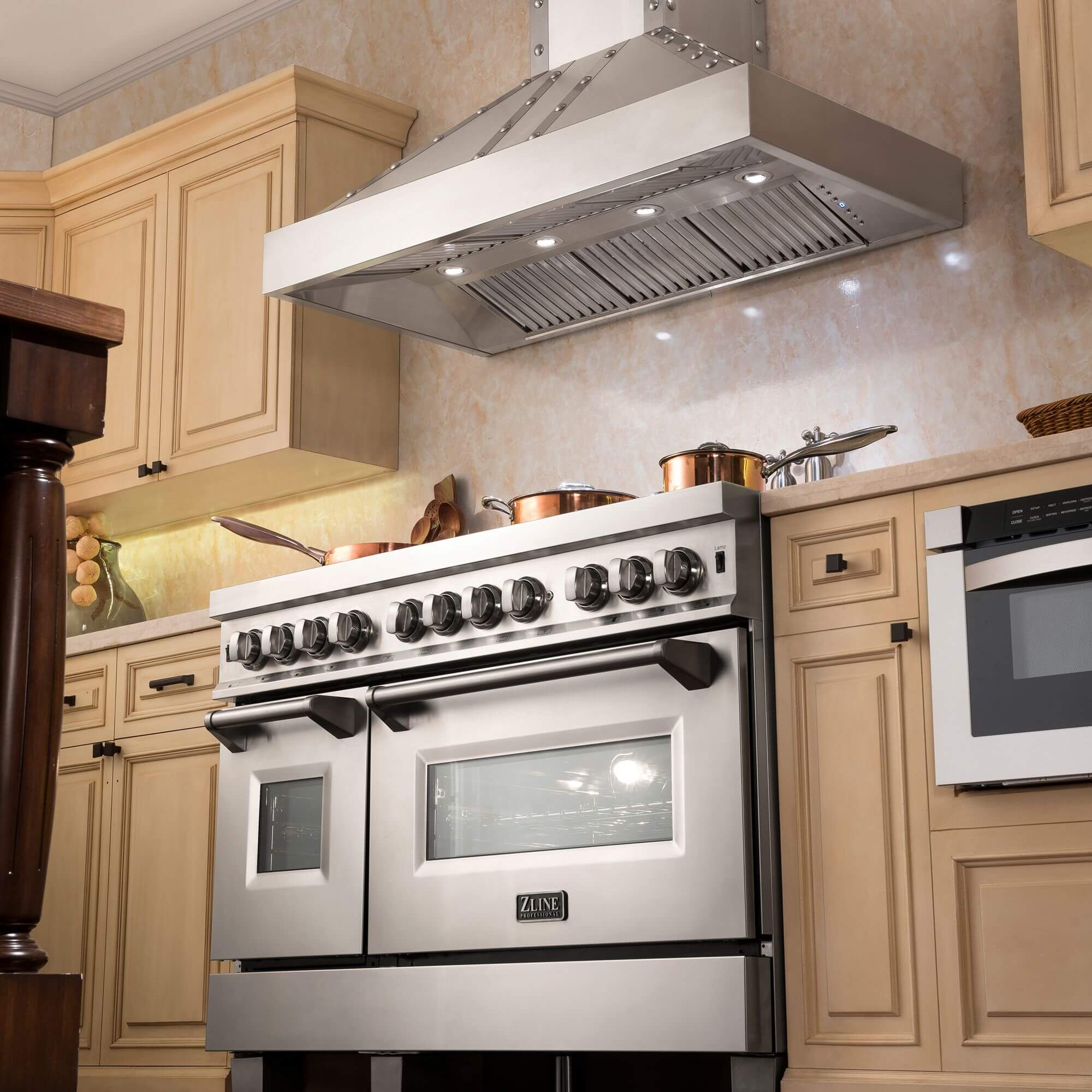 ZLINE Designer Series Wall Mount Range Hood in DuraSnow Stainless Steel with Nailhead Rivets (655-4SSSS) above a double oven range in a luxury kitchen.