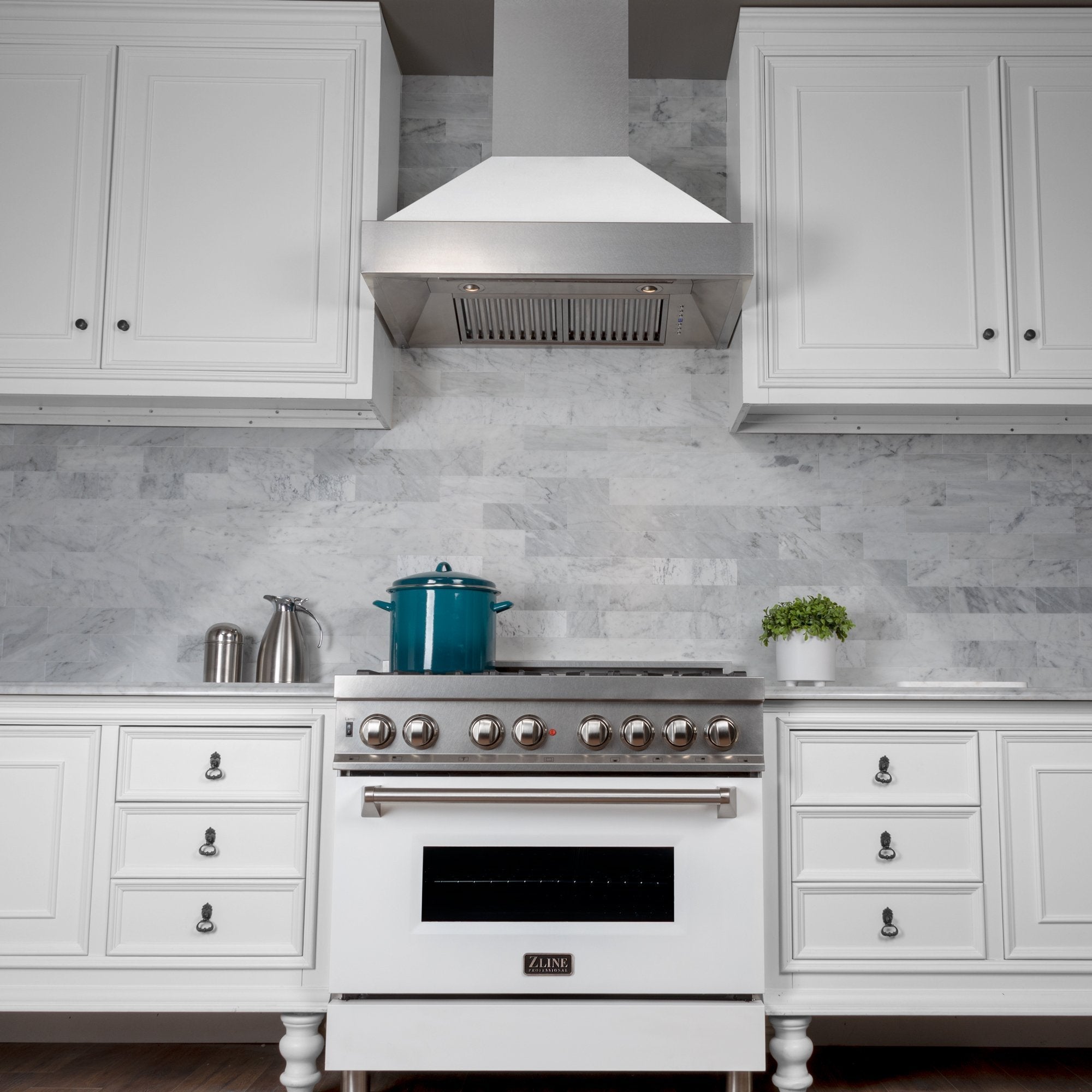 ZLINE Fingerprint Resistant Stainless Steel Range Hood With White Matte Shell (8654WM) with a short chimney above a matching kitchen range from under.