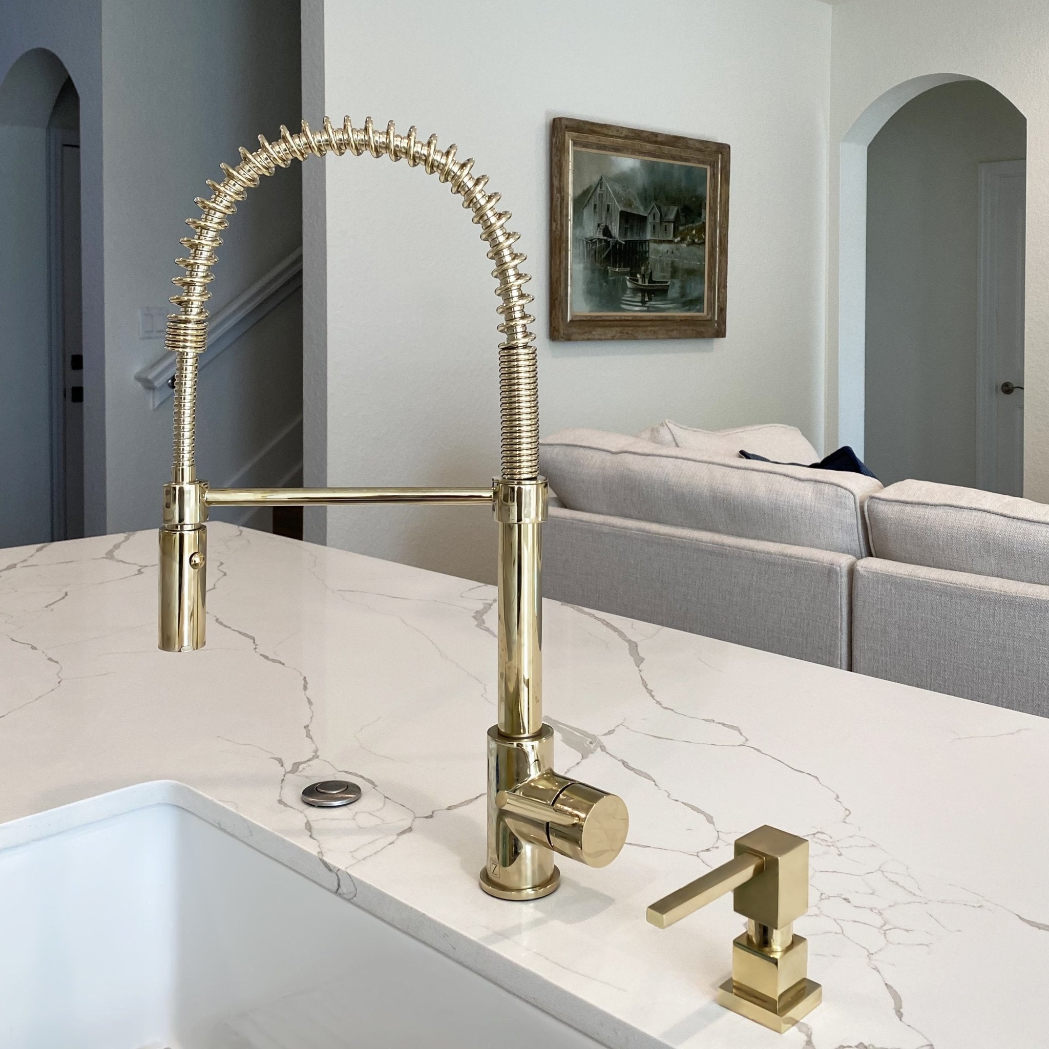 ZLINE Sierra Kitchen Faucet (SRA-KF) with Polished Gold Finish above white marble countertops